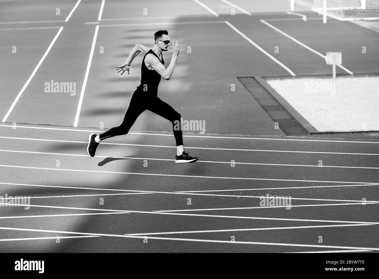 Un jeune athlète court dans le stade vêtu d'un vêtement de sport noir Banque D'Images