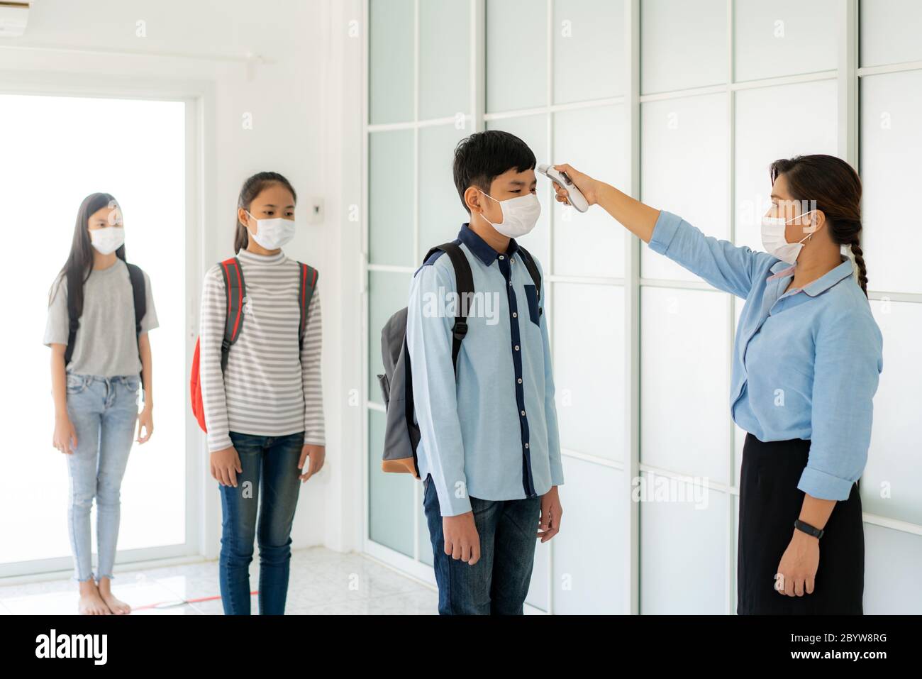 Femme asiatique enseignante utilisant le thermomètre de température de dépistage étudiant pour la fièvre contre la propagation de COVID-19 alors que l'étudiant de retour à l'école, Nouveau Banque D'Images