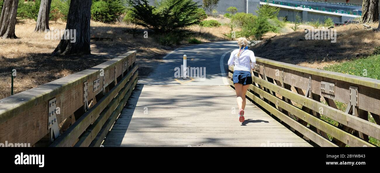 Femme d'âge moyen qui fait du jogging sur un pont-pont lors d'une journée ensoleillée à San Francisco, Californie, États-Unis; femme âgée, coureur; santé, fitness, exercice. Banque D'Images