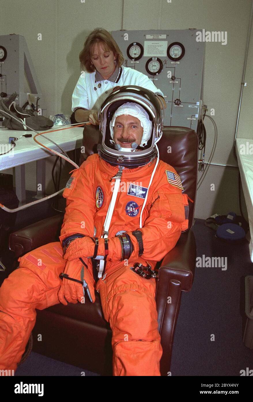 Le commandant de la STS-85 Curtis L. Brown Jr. Sourit alors qu'il est assisté par un technicien de costume dans le bâtiment des opérations et des caisses. Il est lieutenant-colonel de la Force aérienne et il est sur son quatrième vol spatial. Brown a été pilote des STS-47, STS-66 et STS-77. Pilote d'essai, il a plus de 5,000 heures de vol dans un avion à réaction. Brown sera responsable du succès global de ce vol spatial et exploitera et maintiendra Discovery tout au long de la mission. Cela inclut la performance de la tenue de station avec l'Infrase cryogénique Banque D'Images