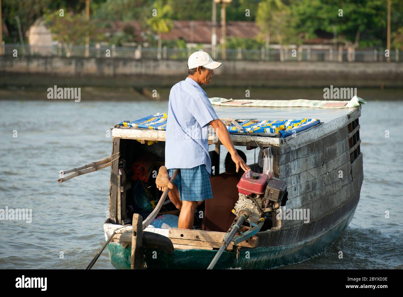 Un homme utilise son pied pour diriger un petit bateau en bois à travers le fleuve Hau à CAN Tho, région du delta du Mékong, sud du Vietnam. Banque D'Images