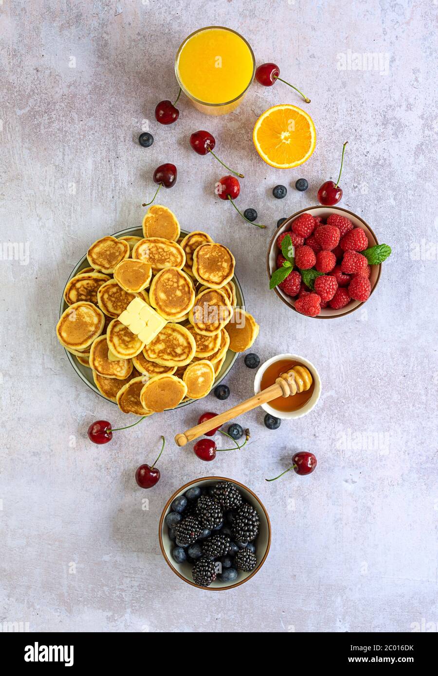 Mini-céréales pancakes avec miel, baies et jus d'orange. Banque D'Images