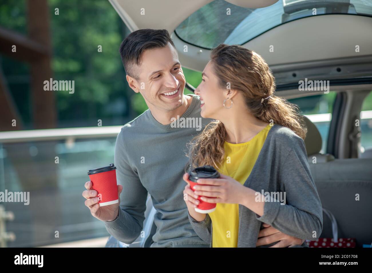 Homme et femme aimant buvant du café près de la voiture. Banque D'Images