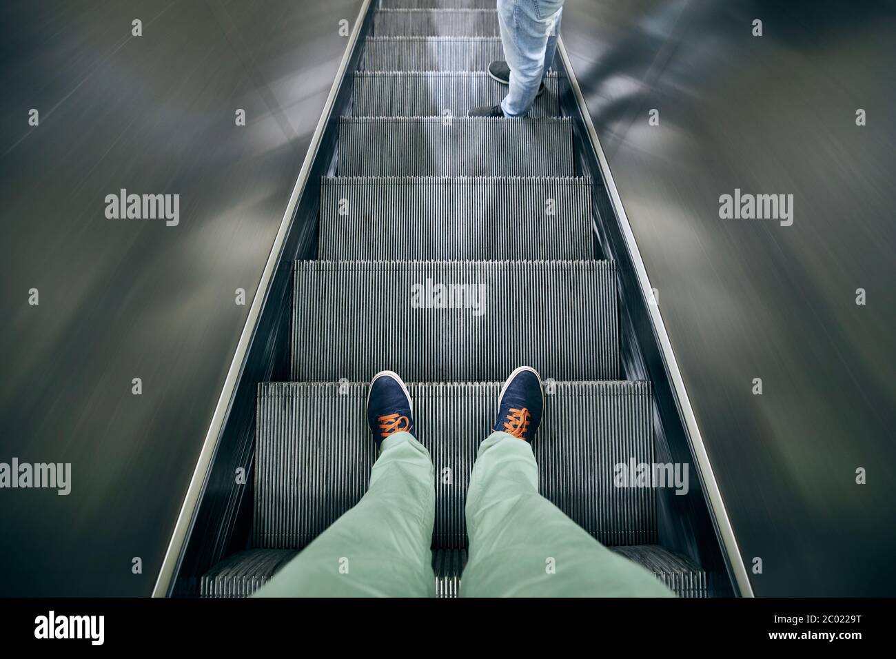 Distanciation sociale au quotidien. Section basse de deux hommes debout sur l'escalier roulant. Distanciation sociale au quotidien. Banque D'Images