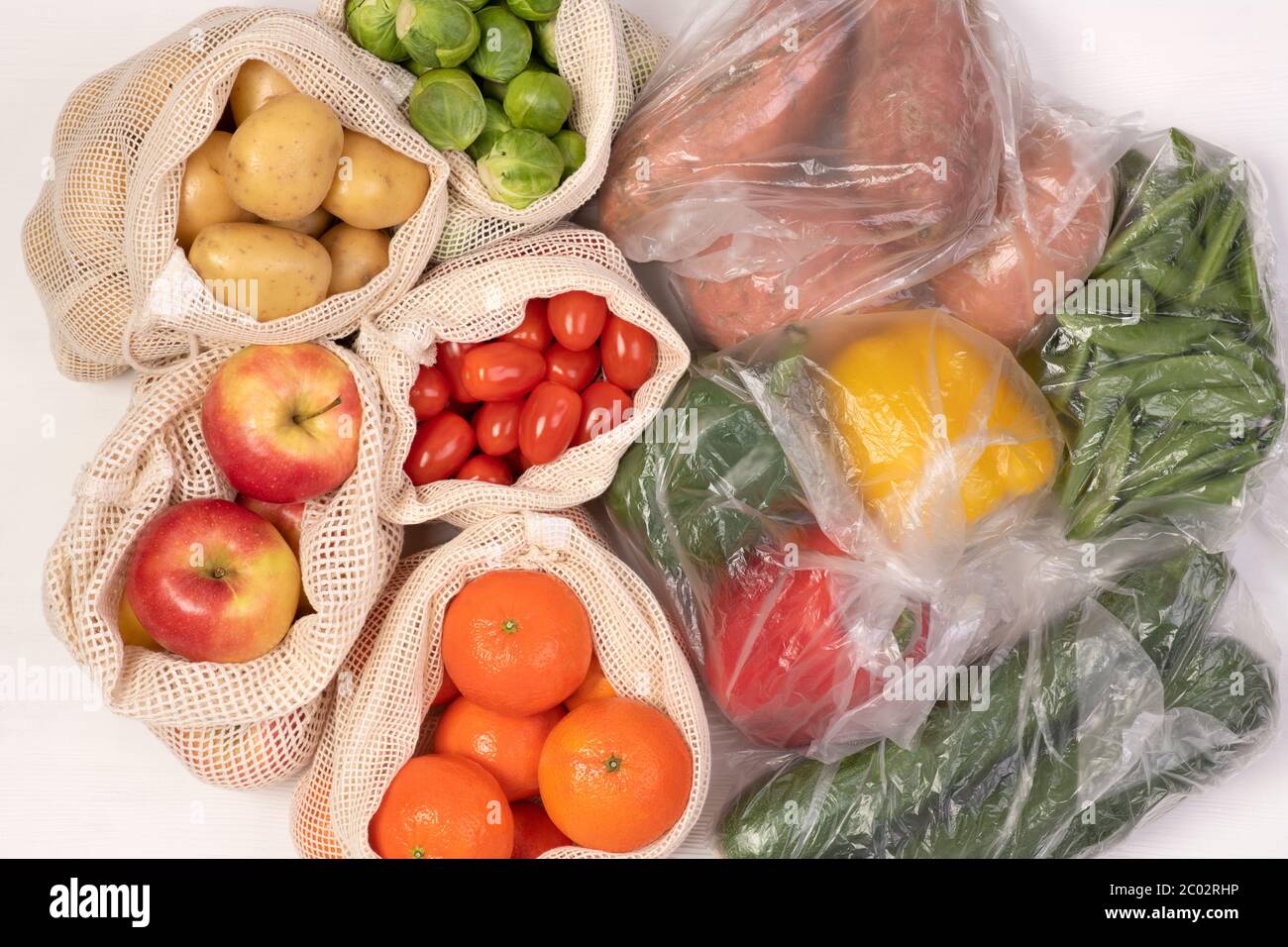 Zéro déchet par rapport aux emballages en plastique. Fruits et légumes dans des sacs en coton réutilisables écologiques et dans des sacs en plastique, vue du dessus Banque D'Images