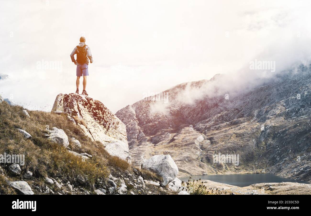 Grimpeur avec un sac à dos sur un jour ensoleillé, un homme s'est mis sur la montagne, les gens voyageant à travers la belle nature sauvage. Banque D'Images