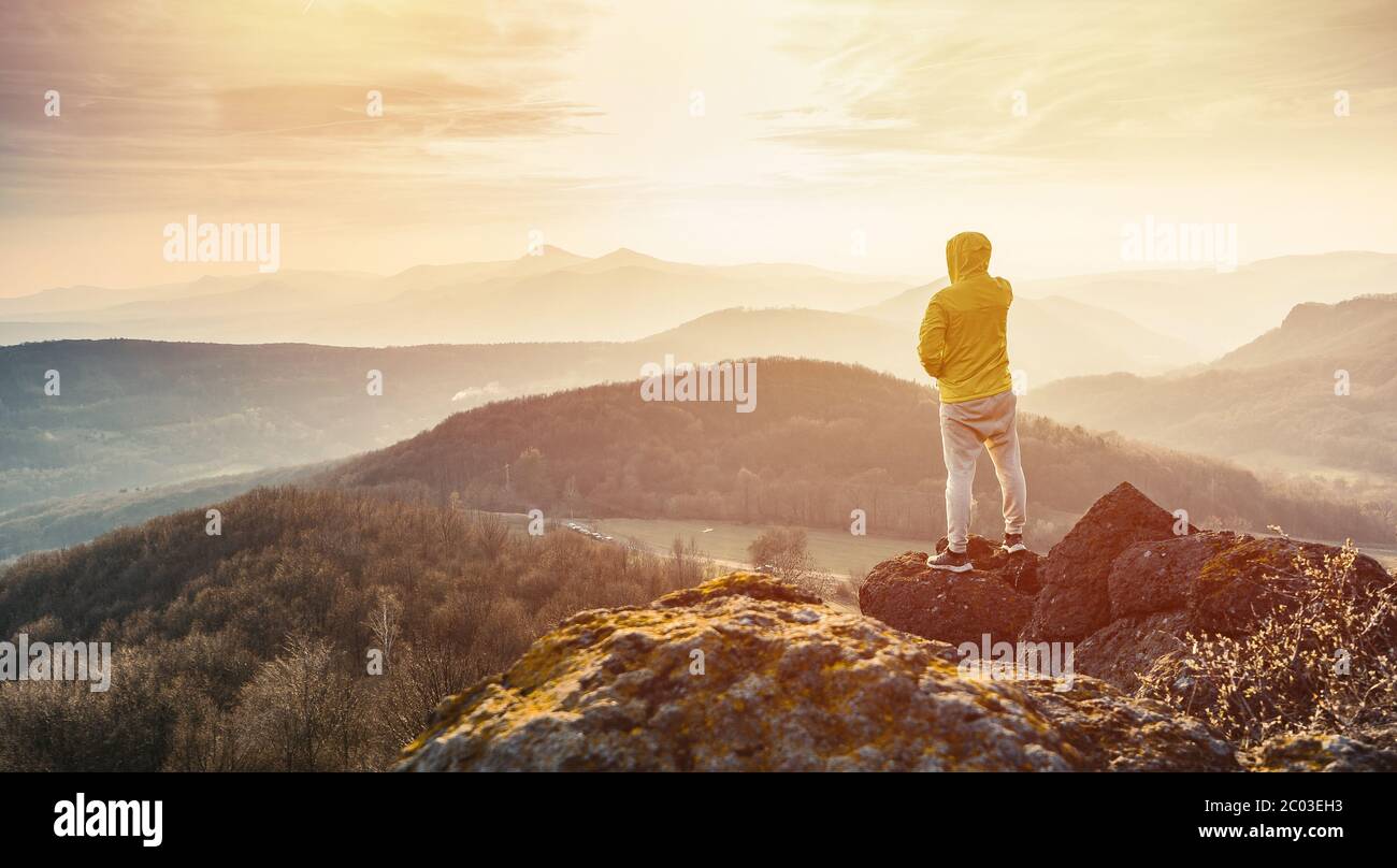 Homme au sommet d'une montagne en pleine ascension. Silhouette d'un homme sur la montagne au coucher du soleil Banque D'Images