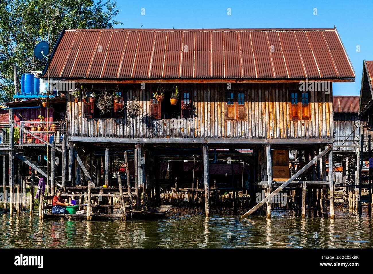 Une femme lave ses vêtements à l'extérieur de sa maison de pilotis sur le lac Inle, État de Shan, Myanmar. Banque D'Images