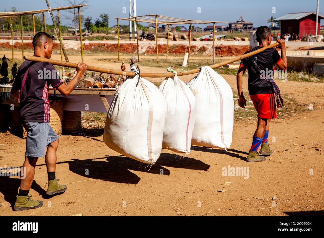 Les jeunes hommes transportent des marchandises par le marché de Thaung Thut, lac Inle, État Shan, Myanmar. Banque D'Images