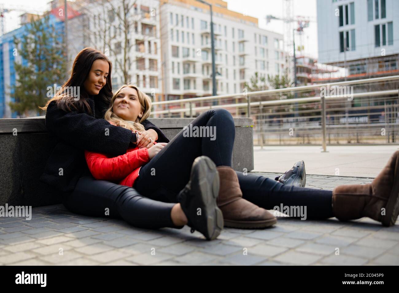 Heureux meilleurs amis se embrassant et assis sur le terrain à la ville Banque D'Images