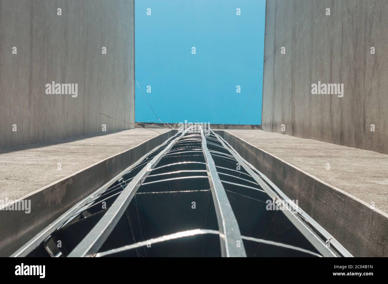 Vue à angle bas d'un escalier d'évacuation de feu externe en spirale d'un bâtiment avec ciel bleu. Banque D'Images