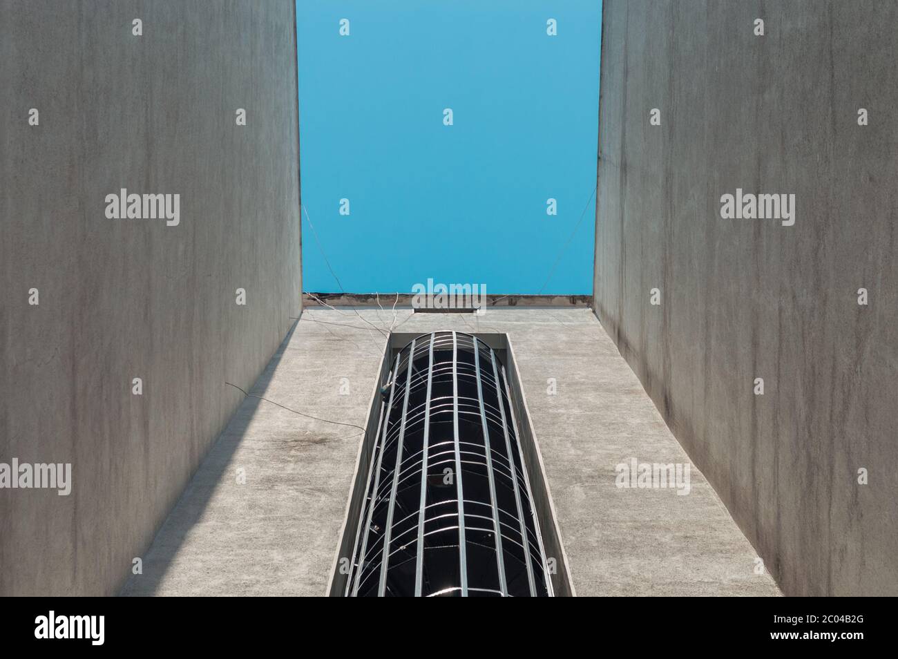Vue à angle bas d'un escalier d'évacuation de feu externe en spirale d'un bâtiment avec ciel bleu. Banque D'Images
