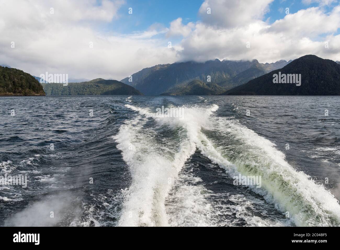 Le sillage d'un bateau qui se déplace rapidement sur le lac de Manapouri en Nouvelle-Zélande avec les montagnes dans le paysage en arrière-plan. Banque D'Images