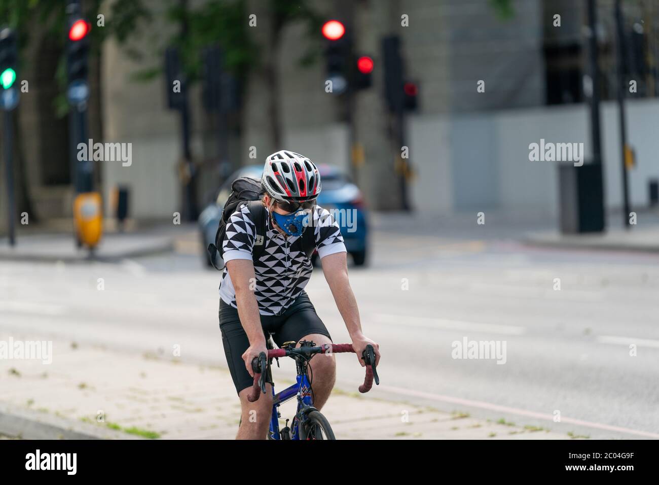 Jeune adulte qui fait du vélo sur une voie de transport le long de l'Embankment, à côté de la Tamise, dans le centre de Londres, en Angleterre, portant un visage Banque D'Images