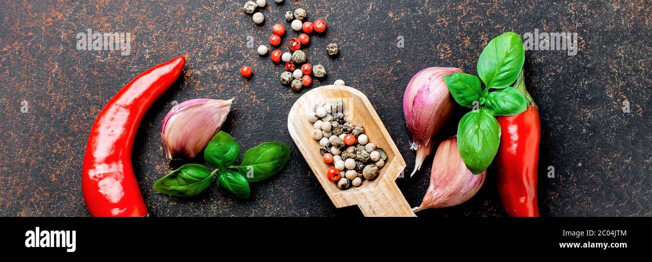 Arrière-plan alimentaire avec espace de copie. Sélection d'épices herbes. Ingrédients pour la cuisson. Poivre rouge, ail, feuilles de basilic, cornes de poivre sur conc. De pierre sombre Banque D'Images