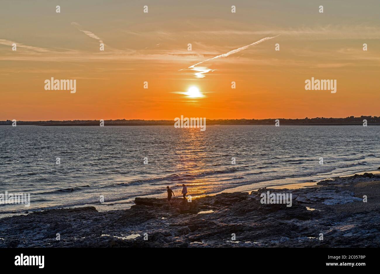 Coucher de soleil sur Porthcawl sur la côte sud du pays de Galles. Photographie prise d'Ogmore par Sea Beach en soirée d'été. Deux personnes sur la mer. Banque D'Images
