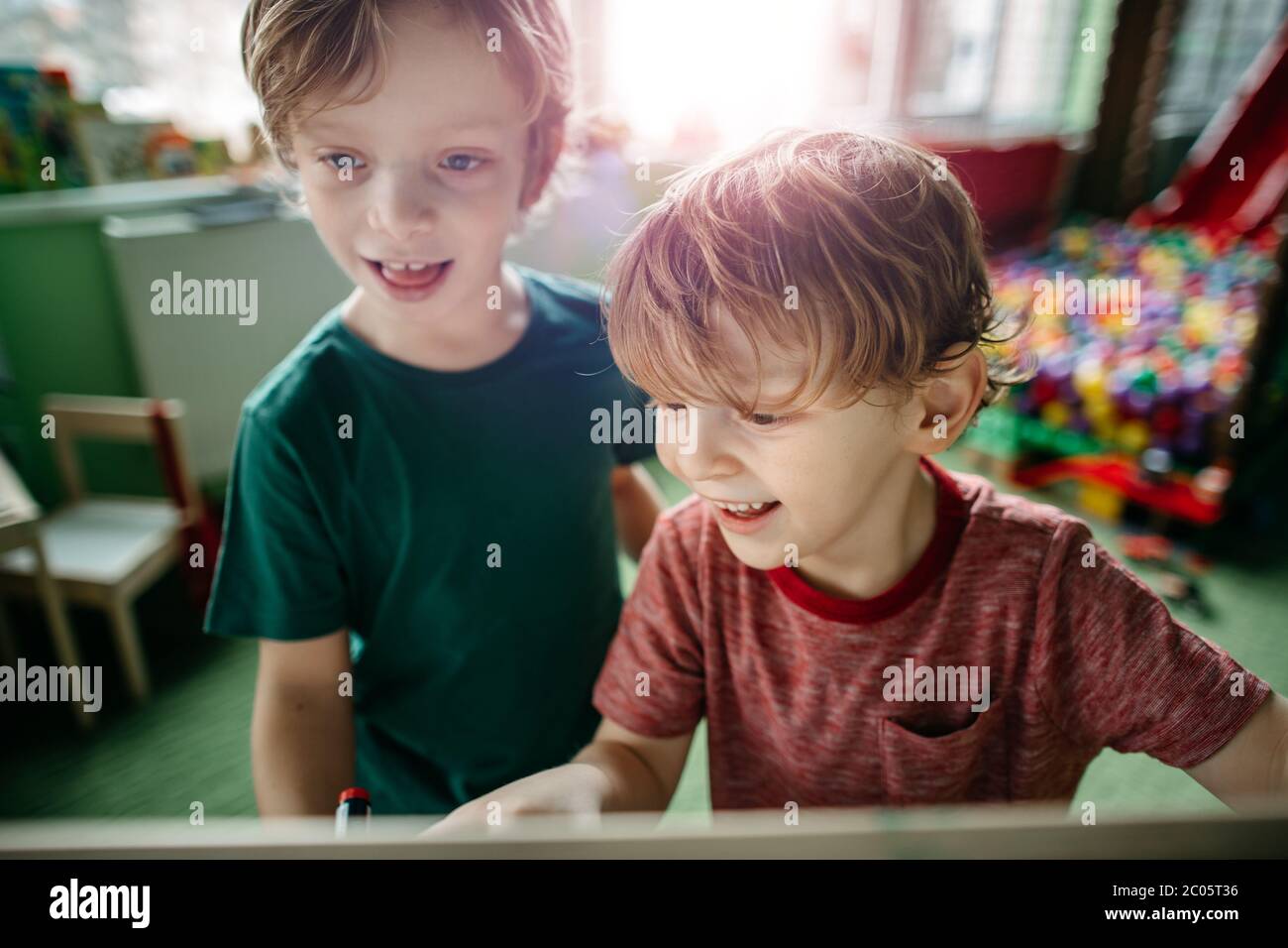 Deux frères s'amusent à dessiner sur une planche dans un terrain de jeu intérieur Banque D'Images