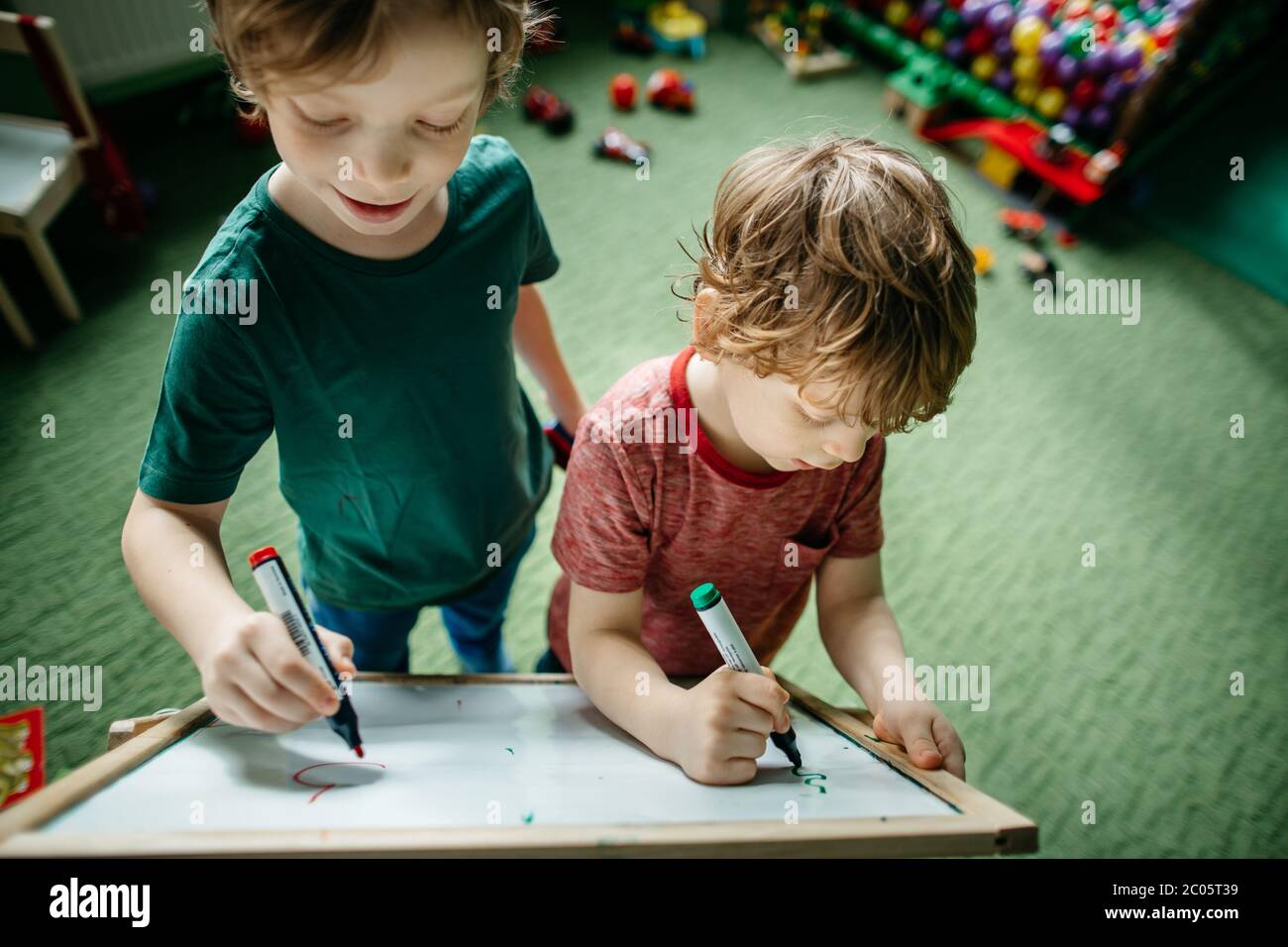 Enfants qui ont du plaisir à écrire sur un tableau à dessin Banque D'Images