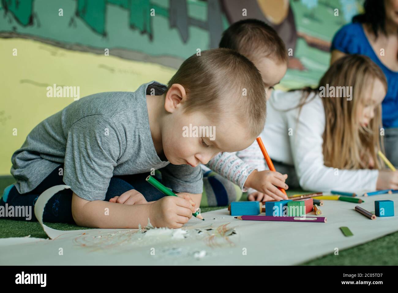 Enfants assis sur le sol et dessin de photos avec des crayons de couleur Banque D'Images