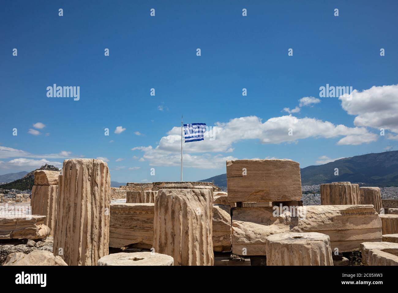 Acropole d'Athènes, Grèce. Drapeau grec agitant sur le poteau, ancienne colonne reste sur fond bleu ciel, printemps jour ensoleillé. Banque D'Images