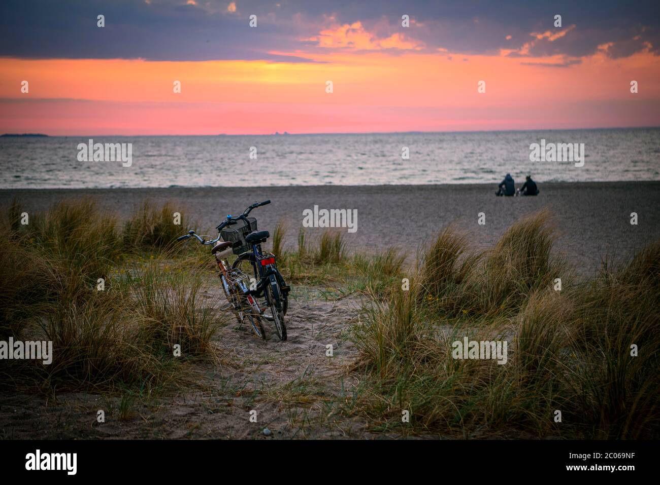 Vélos et couple sur la plage d'Amager au lever du soleil, Copenhague, Danemark Banque D'Images
