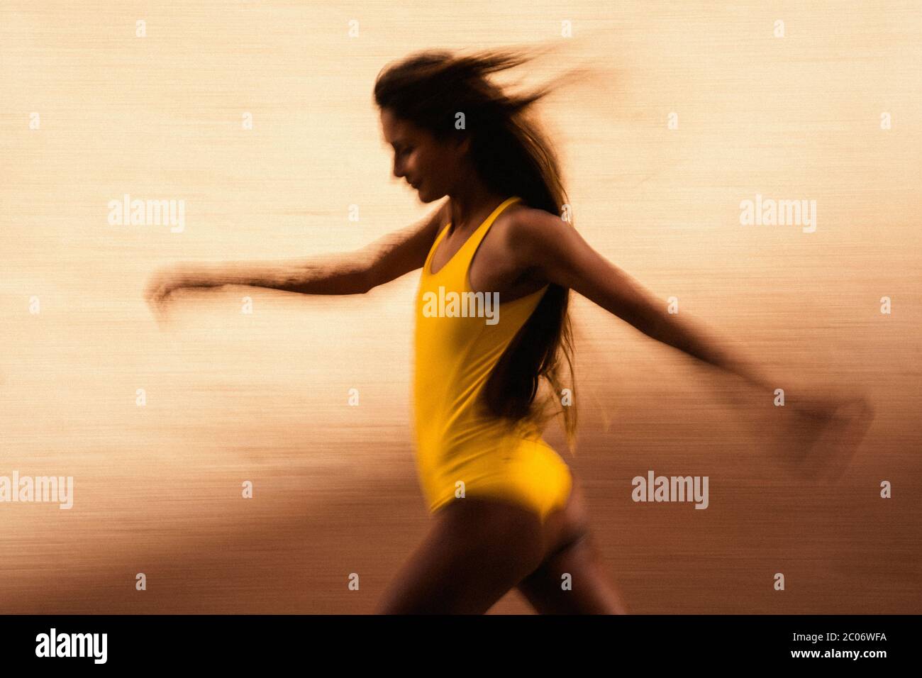 Flou artistique de vitesse de jeune femme courir contre le mur jaune Banque D'Images