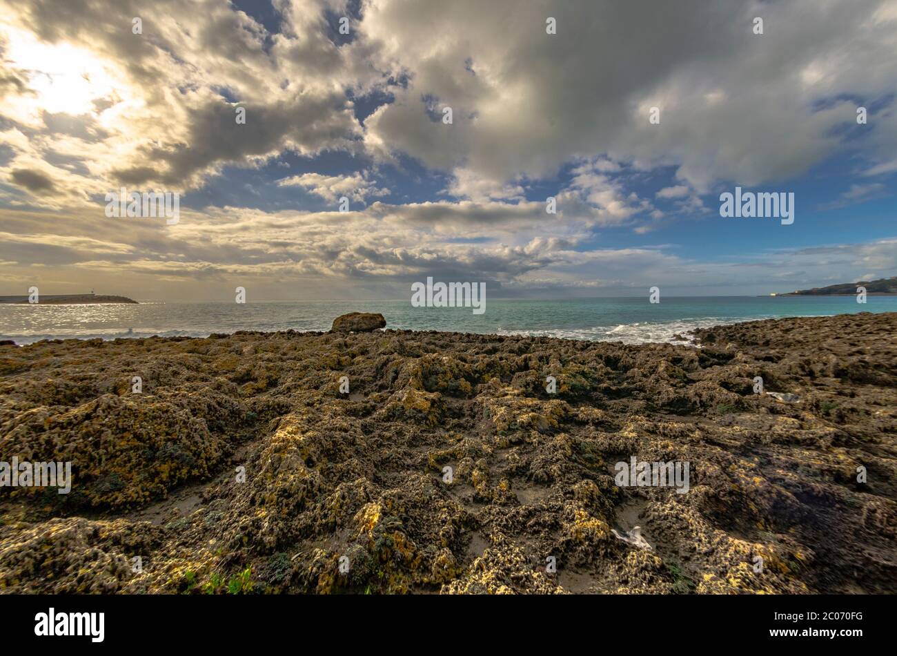 Coucher de soleil sur la mer avec rochers et ciel nuageux Banque D'Images