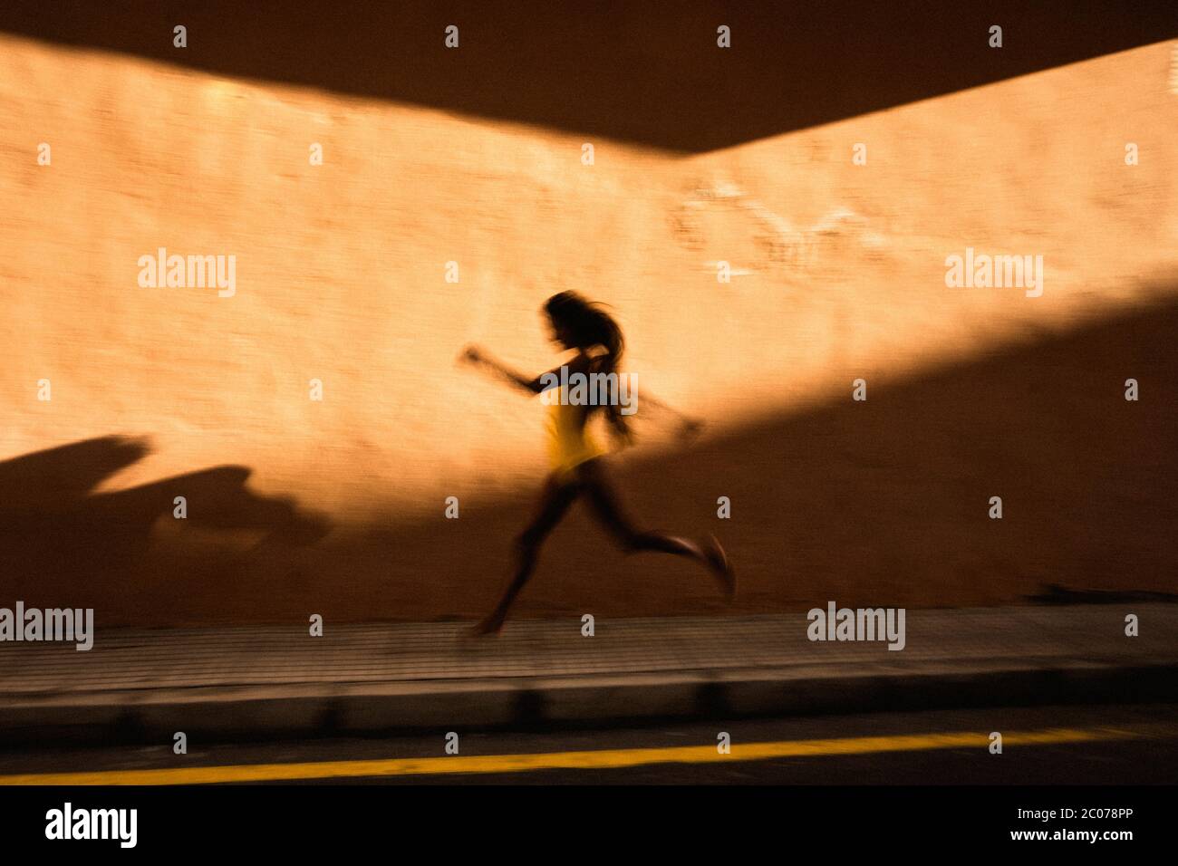 Flou artistique de vitesse de jeune femme courir contre le mur jaune Banque D'Images