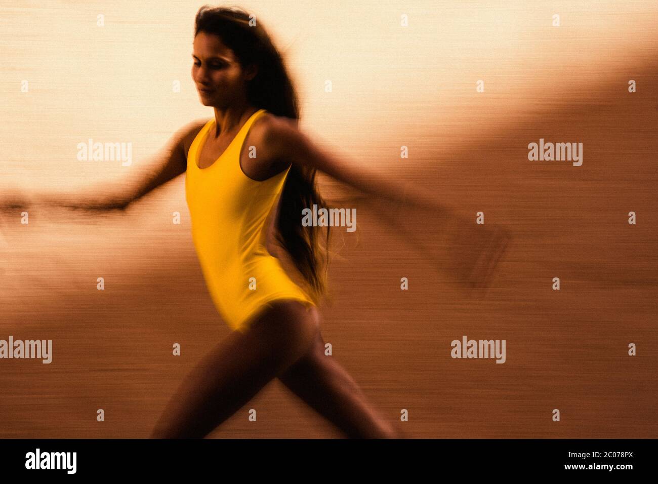 Flou artistique de vitesse de jeune femme courir contre le mur jaune Banque D'Images