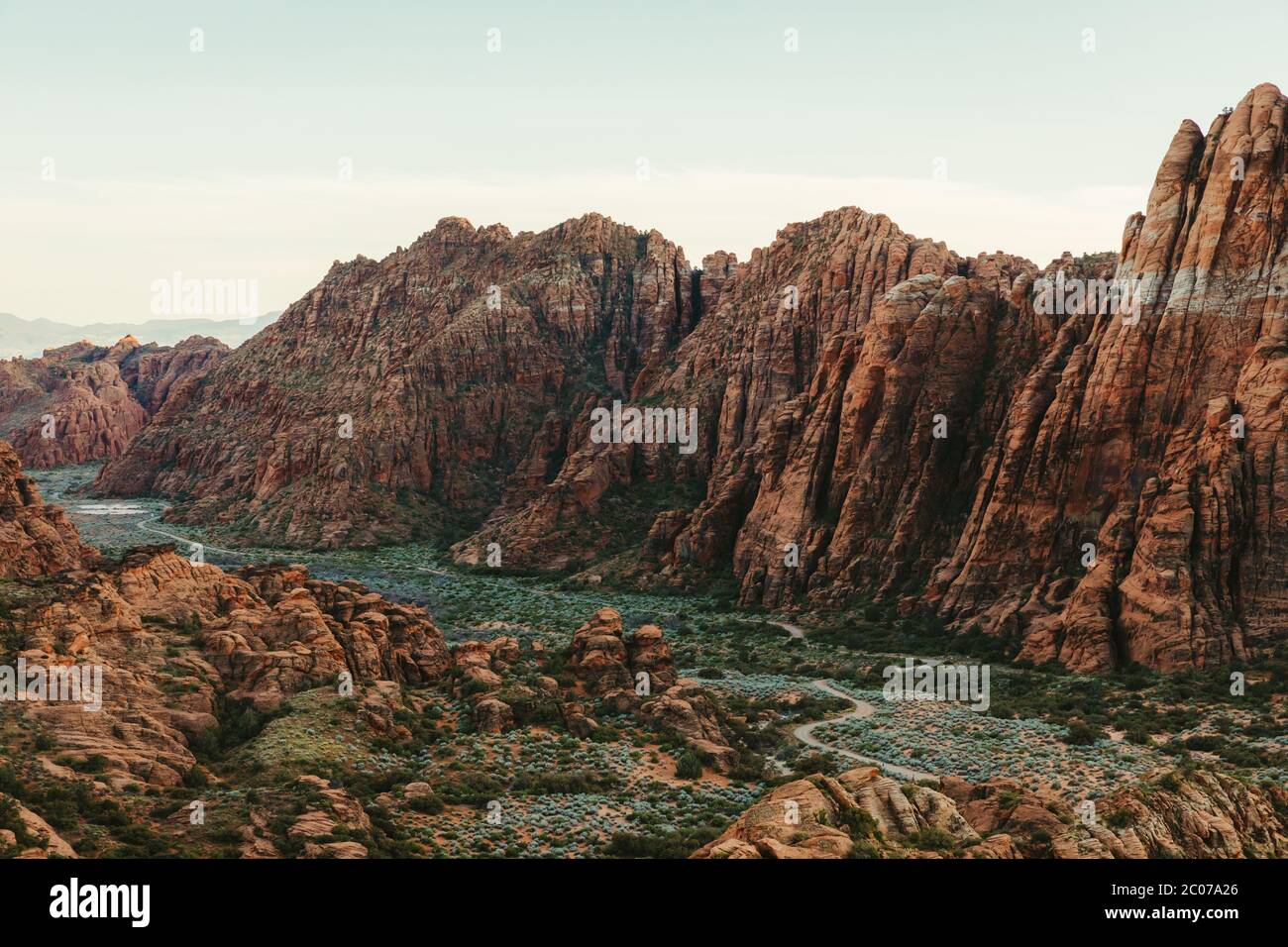 Falaises rouges du parc national de Snow Canyon avec route verte de la vallée en dessous Banque D'Images