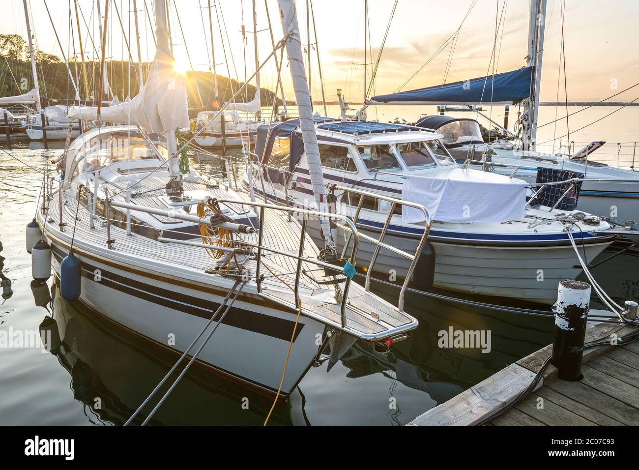 Bateaux à voile dans une marina pendant un beau coucher de soleil doré sur la mer Baltique Banque D'Images