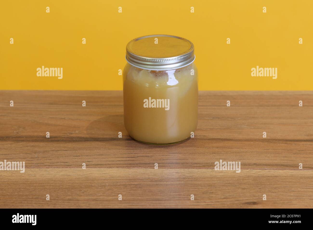 Un pot de miel naturel crémeux non étiqueté contre jaune Banque D'Images