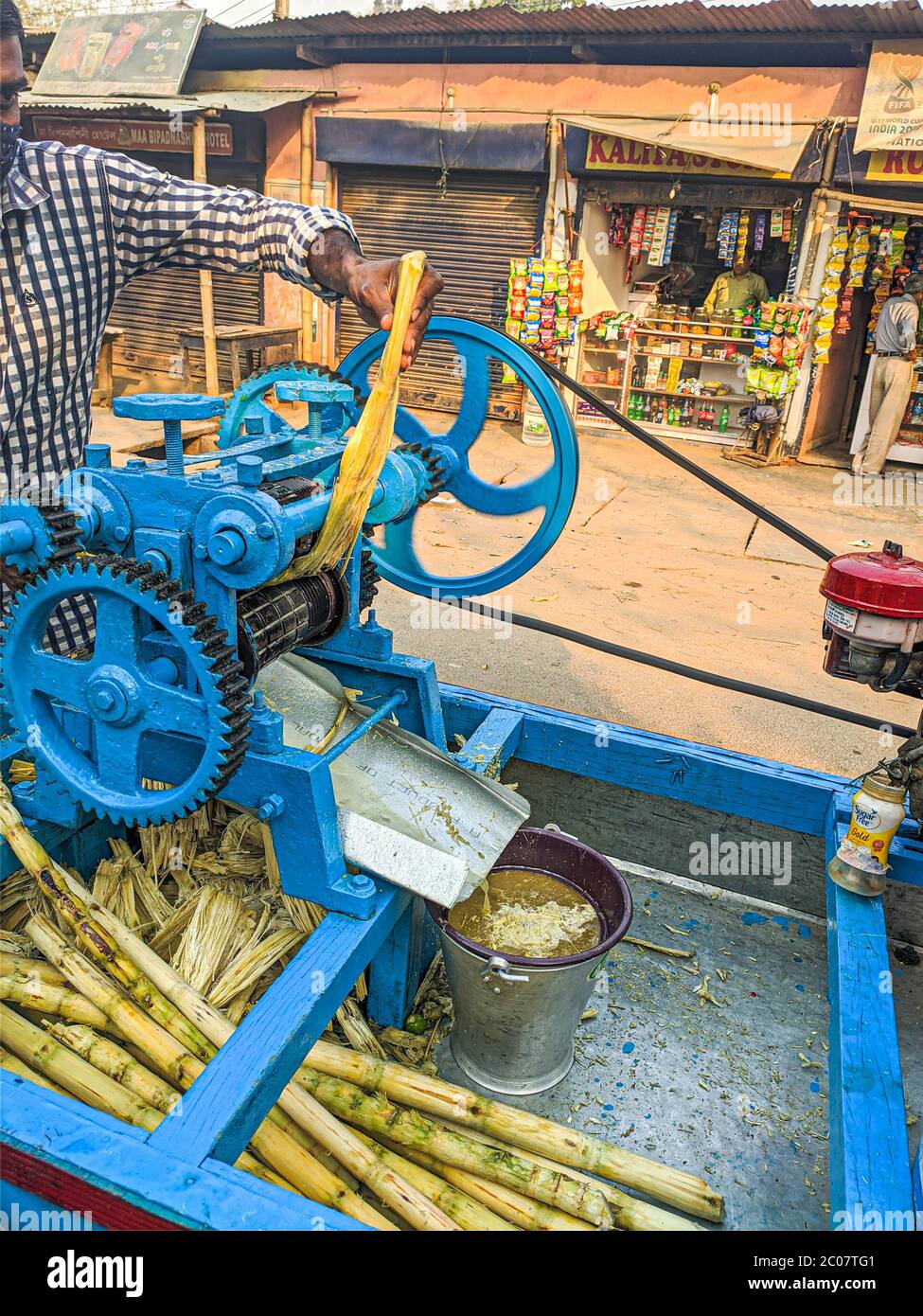 Street Side sugarcane Juice Maker, faisant le jus en écrasant les sucreries. Banque D'Images