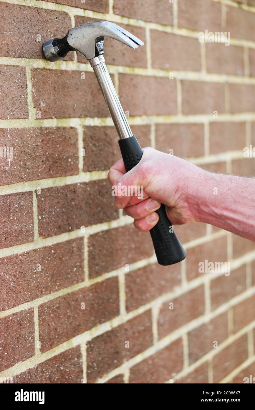 Homme frappant un mur de briques avec un marteau Banque D'Images