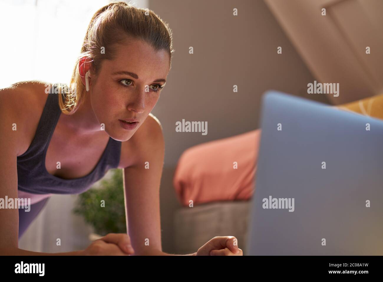 Jeune femme prenant part à un cours de fitness en ligne devant un ordinateur portable. Banque D'Images