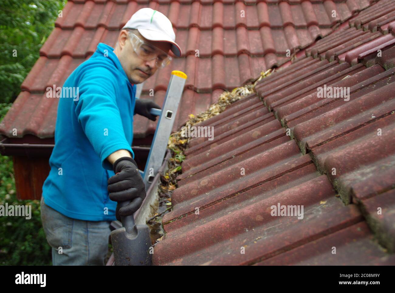 Homme sur l'échelle nettoie la gouttière sur le toit. Entretien d'une  maison privée Photo Stock - Alamy
