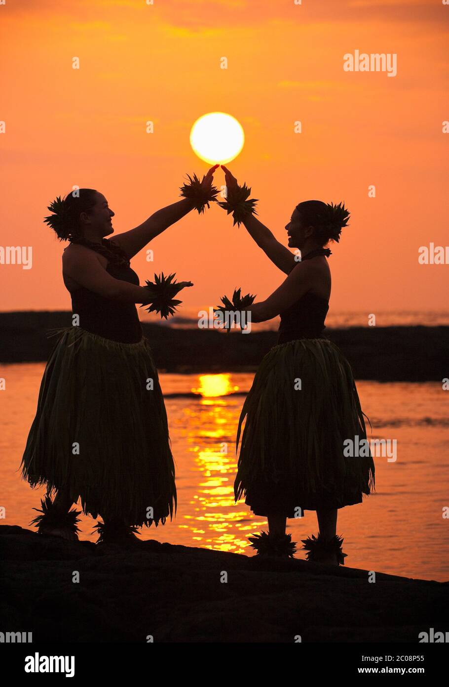 Les danseurs hula traditionnels (modèle relâché) semblent tenir le soleil au coucher du soleil au parc national Puuhonua O Honaunau à Hawaï Banque D'Images