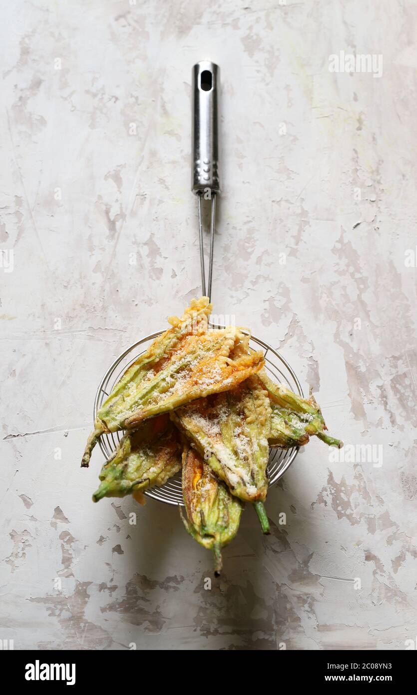 Concept des légumes. Fleurs de courgettes frites dans de la pâte et saupoudrées de parmesan sur fond clair. Vue de dessus. Banque D'Images