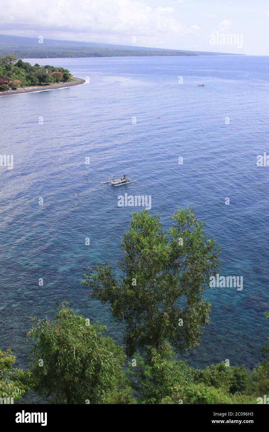 Amed Bay à Bali horizontal. Amed est devenu une destination touristique populaire et est situé sur la côte est de Bali. Ici, un voilier quitte le calme Banque D'Images