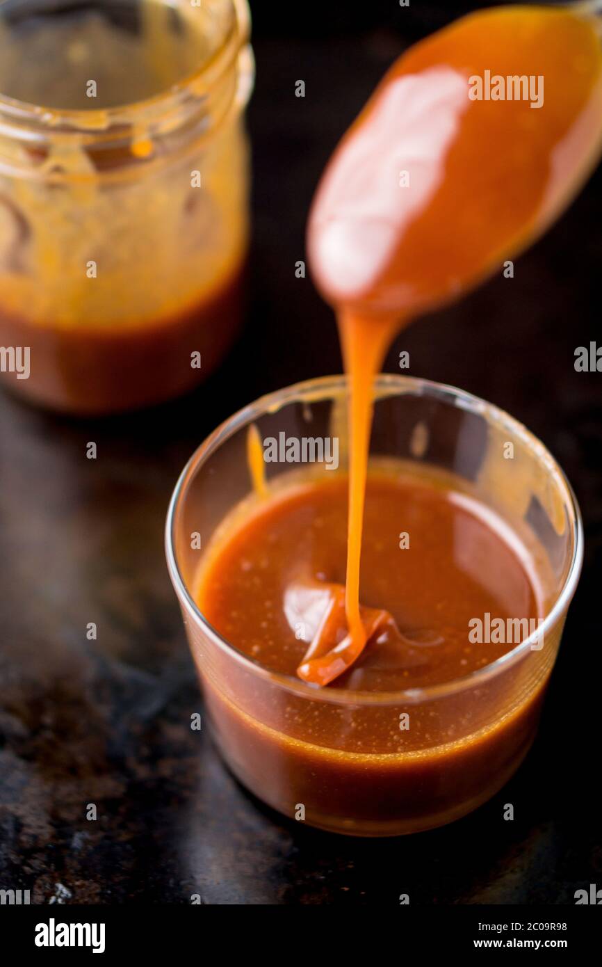 Suer la sauce caramel qui s'égoutte d'une cuillère. Cette délicieuse sauce caramel peut être utilisée comme garniture pour ajouter de la saveur aux gâteaux, à la crème glacée et à de nombreux autres desserts Banque D'Images