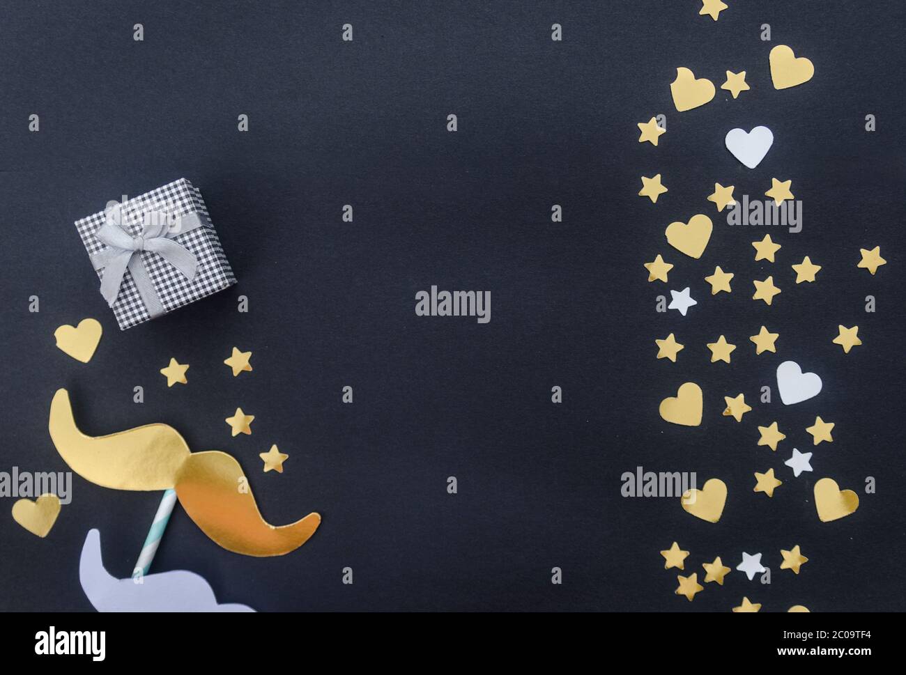Concept de fête des pères heureux : moustache, étoiles présentes et dorées sur fond noir. Flat lay, vue de dessus, espace de copie. Banque D'Images