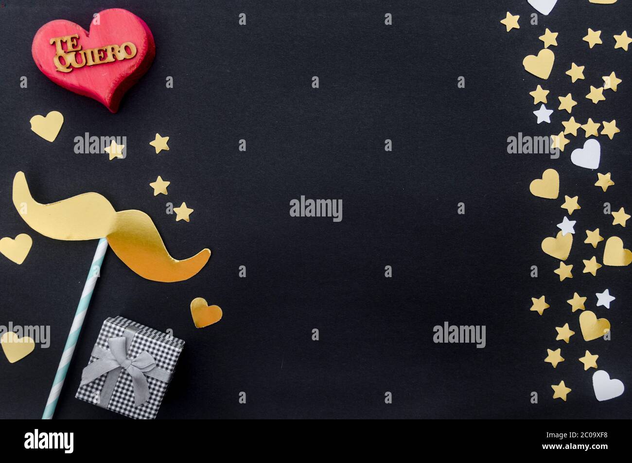 Concept de la fête des pères : cadeau, moustache, cœur et étoiles sur fond noir avec le mot en espagnol pour « Je t'aime ». Flat lay, vue de dessus, espace de copie. Banque D'Images