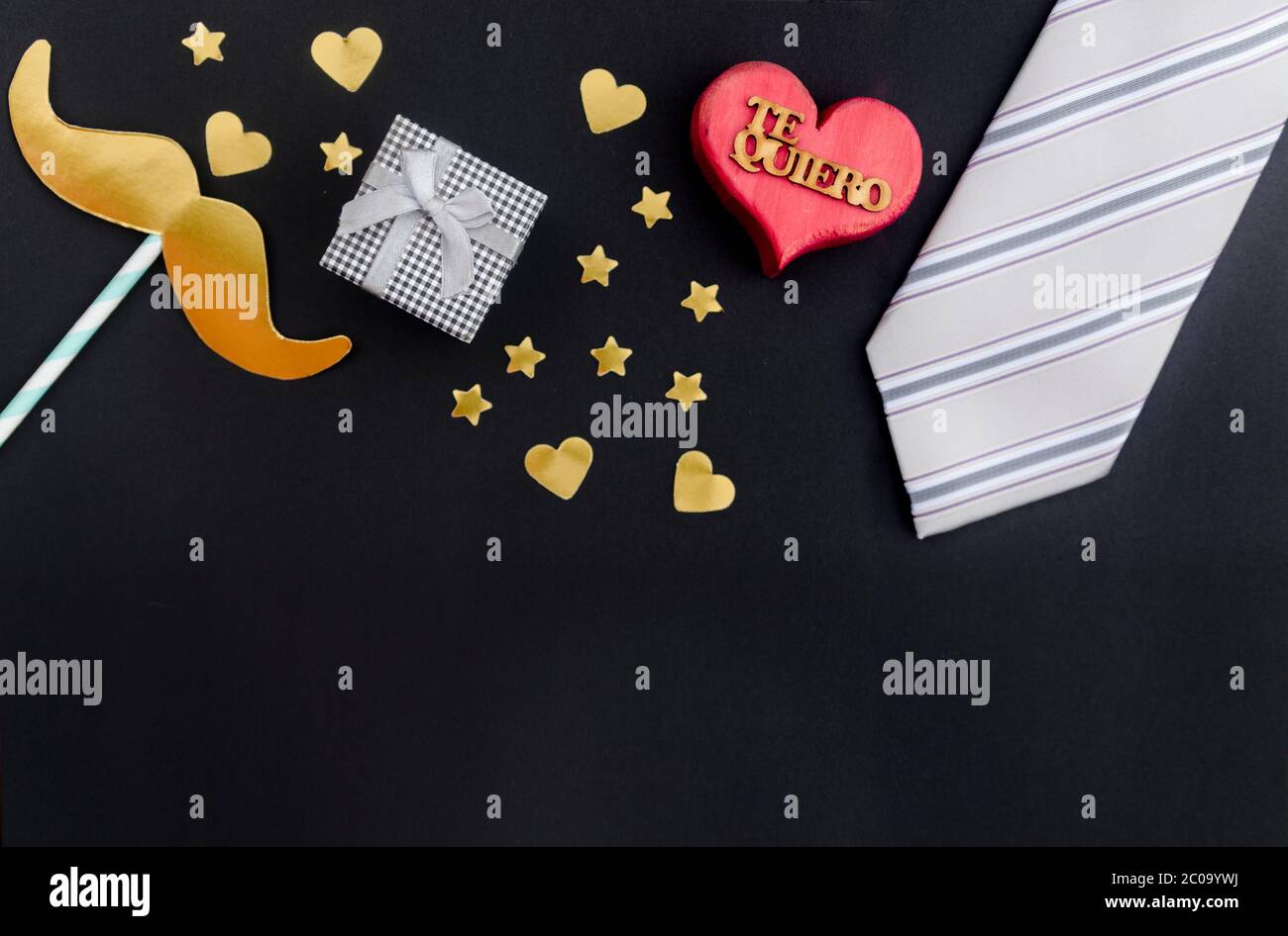 Concept de la fête des pères : cadeau, moustache, cœur et étoiles sur fond noir avec le mot en espagnol pour « Je t'aime ». Flat lay, vue de dessus, espace de copie. Banque D'Images