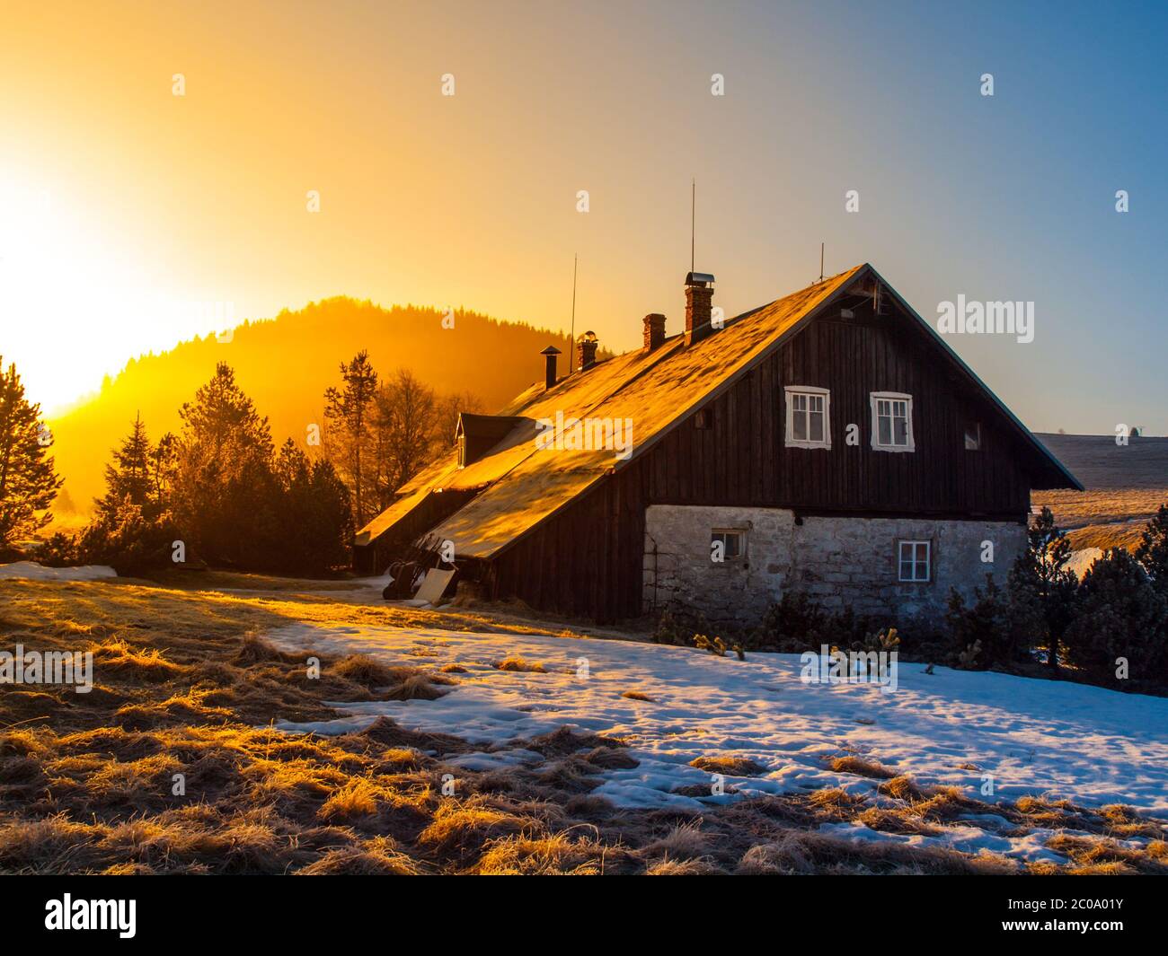Cabane de montagne dans les premiers faisceaux de soleil levant. Matin de montagne libre en hiver. Banque D'Images