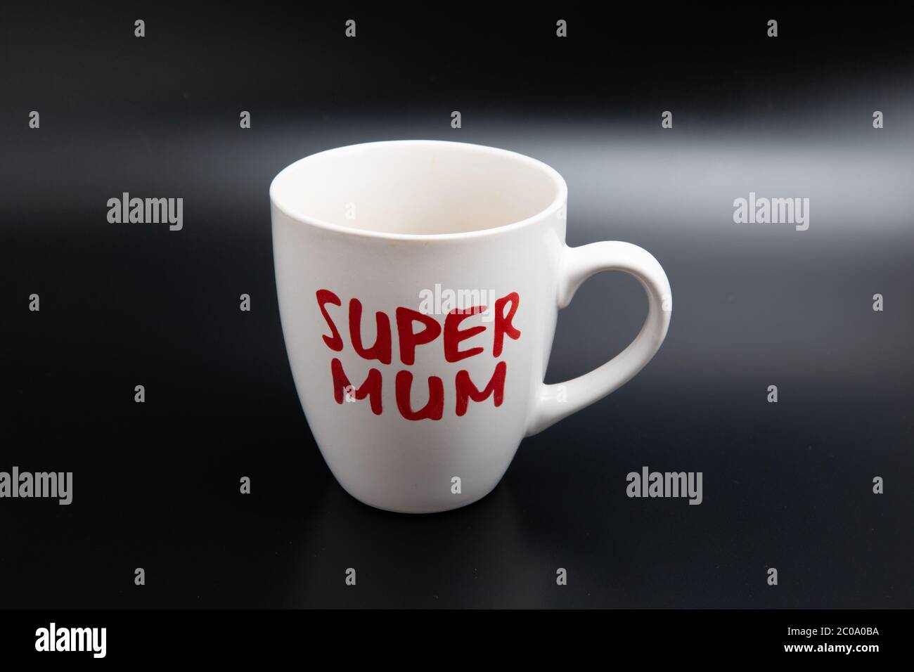 Gros plan d'une tasse à café blanc super maman vide isolée sur fond noir avec espace de copie Banque D'Images