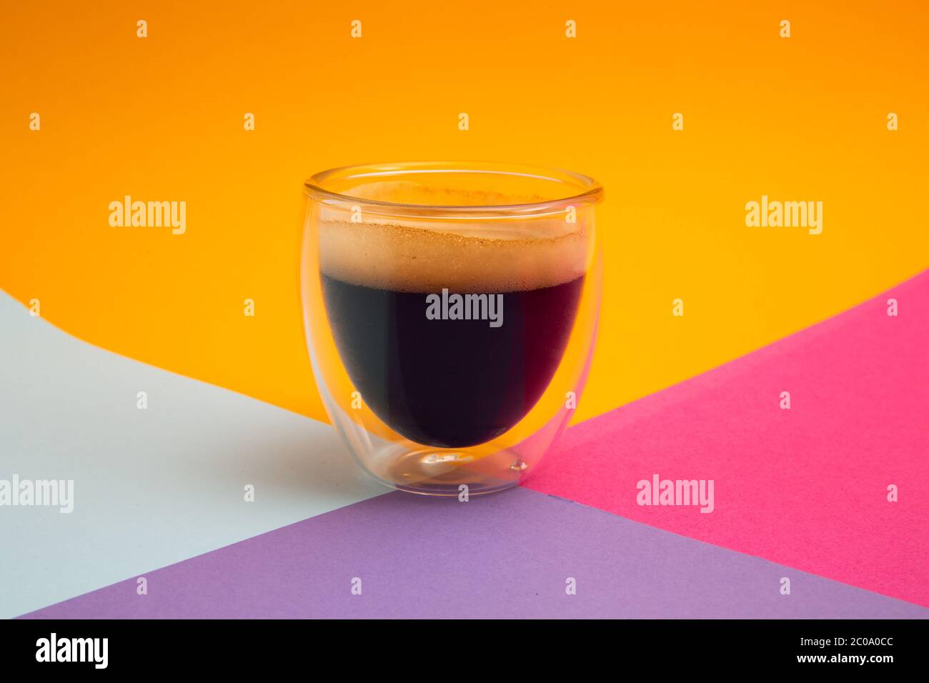 Espresso crémeux fraîchement préparé dans une tasse de café en verre isolée sur fond coloré, en gros plan avec l'espace de copie Banque D'Images