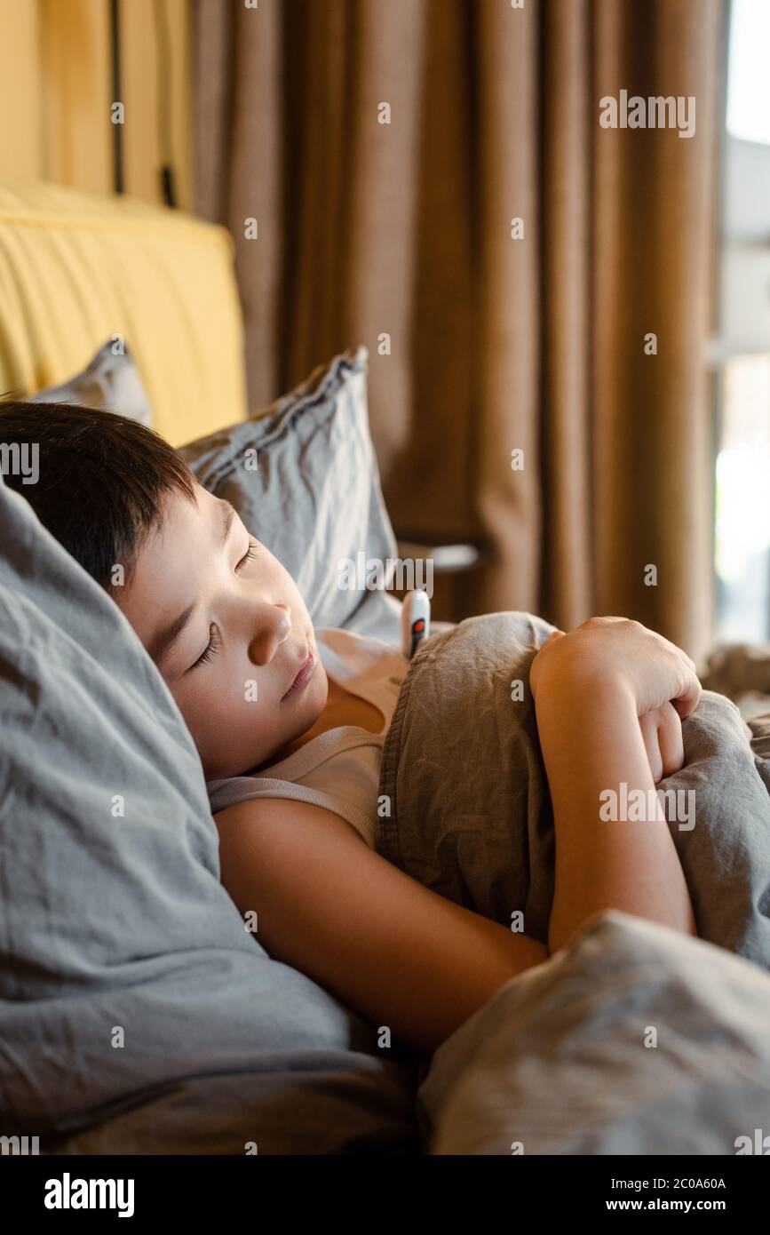 malade asiatique garçon avec thermomètre dormant dans le lit en quarantaine Banque D'Images