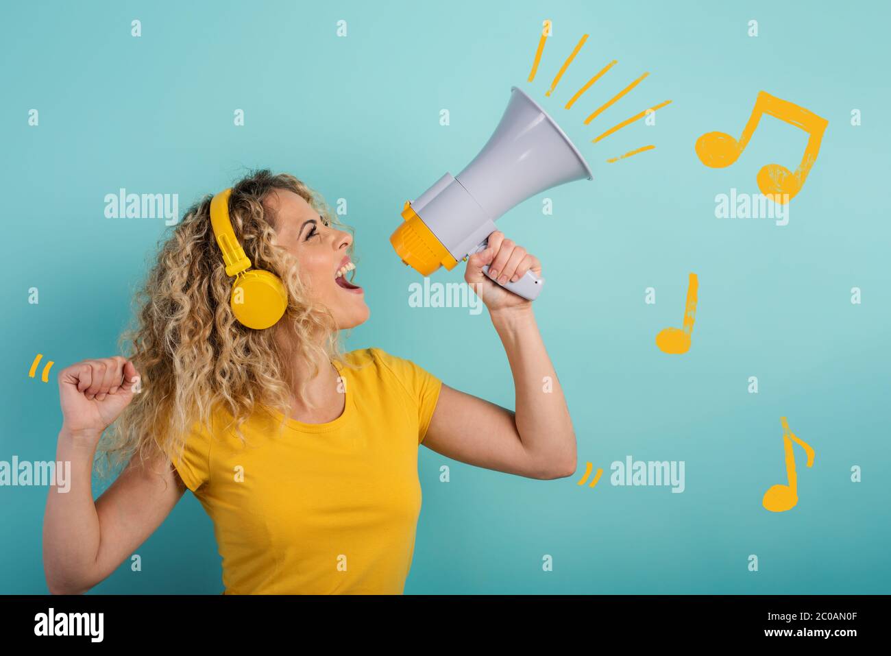 Femme chante avec haut-parleur et écoute de la musique avec casque. Expression joyeuse. Fond cyan Banque D'Images