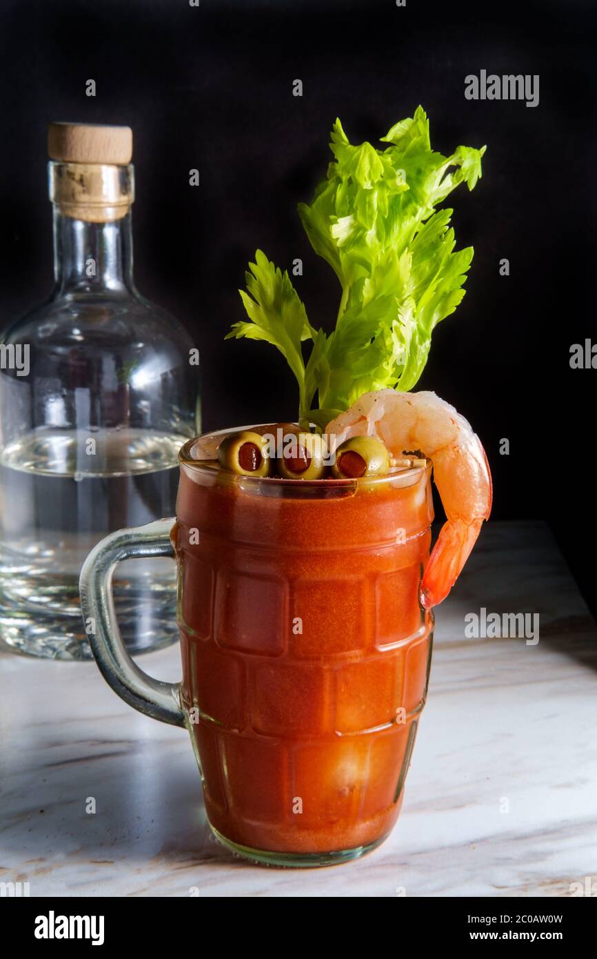 Cocktail de vodka Bloody Mary dans une bière stein avec garniture aux crevettes sur une table de cuisine en marbre Banque D'Images