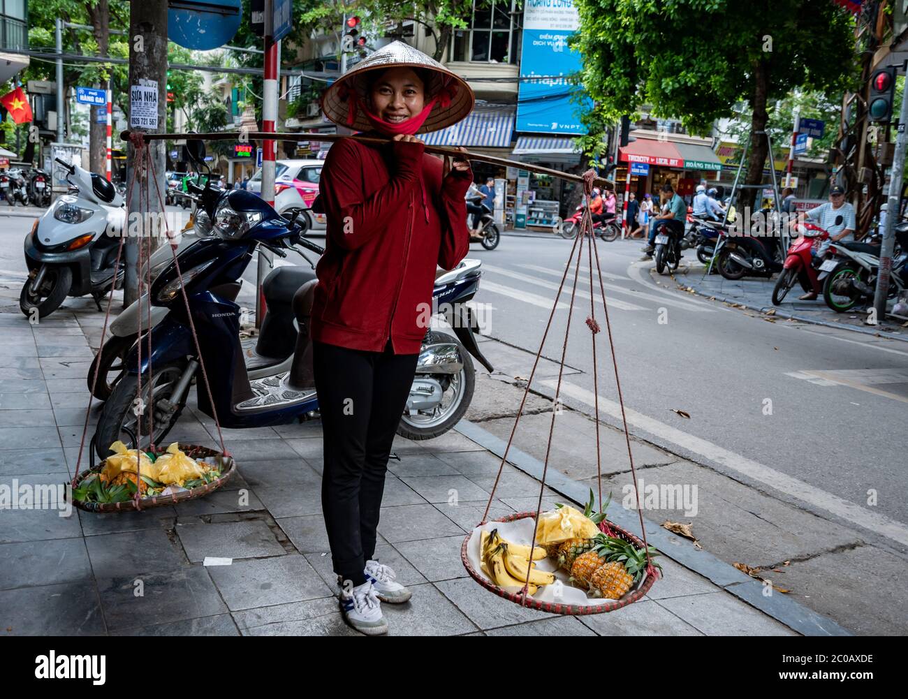 Jeune femme vietnamienne, accueillante et souriante, tout en vendant des fruits frais dans la rue. Banque D'Images